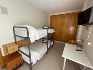 a small room with two bunk beds and a desk at Residencial Oscense in Huesca