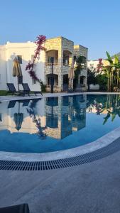 una piscina frente a un edificio con sombrillas en Sun Garden Apart Hotel, en Yalıkavak