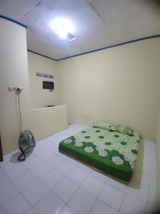 ein Schlafzimmer mit einem grünen Bett in einem Zimmer in der Unterkunft Narika Guest House in Grogol