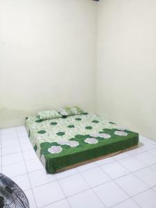 un letto in una camera con coperta verde e bianca di Narika Guest House a Grogol