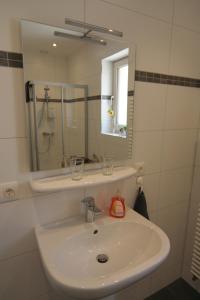 een witte badkamer met een wastafel en een spiegel bij B&B White Pearl in Müllerthal