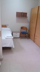 - une chambre avec un lit et une chaise dans l'établissement Residencial Oscense, à Huesca