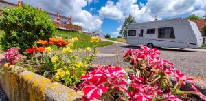 a white rv parked in a driveway with flowers at Tiny House in Chvalšiny