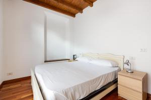 ein Schlafzimmer mit einem weißen Bett und einer Holzkommode in der Unterkunft Porta Romana M3- Cosy apartament in Mailand