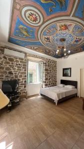 - une chambre avec un lit et un plafond orné de peintures dans l'établissement Royal House, à Kotor