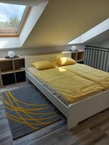 ein Schlafzimmer mit einem Bett mit gelber Bettwäsche und einem Fenster in der Unterkunft Gemini Apartman in Esztergom