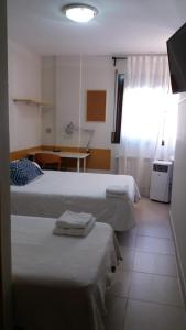 1 dormitorio con 2 camas, mesa y ventana en Residencial Oscense, en Huesca