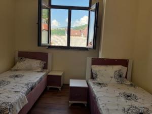 two beds in a room with a window at Center Side in Prizren