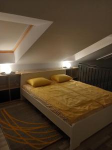 a bedroom with a bed with two yellow pillows at Gemini Apartman in Esztergom