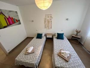 2 camas en una habitación con almohadas azules y lámpara en Maison de village chez Audrey, en Ramatuelle