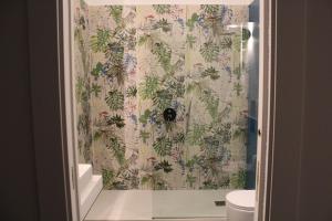 a bathroom with a shower with a floral shower curtain at Casa Gaia in Naples