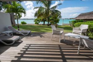 a deck with chairs and a table and the ocean at VILLA PIEDS DANS L'EAU - GRAND BAIE in Grand-Baie