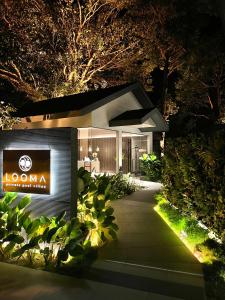 a home lit up at night with a sign on it at Looma Private Pool Villas in Pantai Cenang