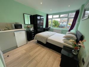 a small bedroom with a bed and a kitchen at Letzi Private En-Suite, Near Heathrow Airport T3 in Hayes