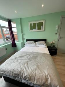 a large bed in a room with green walls at Letzi Private En-Suite, Near Heathrow Airport T3 in Hayes