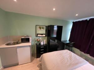 a bedroom with a bed and a sink and a kitchen at Letzi Private En-Suite, Near Heathrow Airport T3 in Hayes
