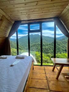 un letto in una camera con una grande finestra di Mtirala Skhivi Cottage a Batumi