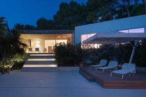 a house with two chairs and an umbrella at Mordern Villa - Sea view - Near Eivissa old town in Can Furnet