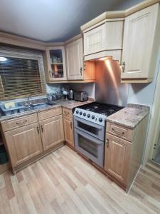 a kitchen with wooden cabinets and a stove top oven at Wonderful 2 bedroom mobile home in Aberystwyth