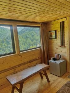 バトゥミにあるMtirala Skhivi Cottageのベンチと大きな窓が備わる木造の客室です。