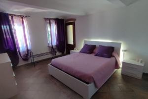 ein Schlafzimmer mit einem Bett mit lila Bettwäsche und lila Kissen in der Unterkunft La casa di giuda in Vigliano d'Asti