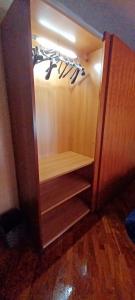 a wooden cabinet with hangers and wine glasses in it at La Rosa dei Venti Guest House in Pontecagnano