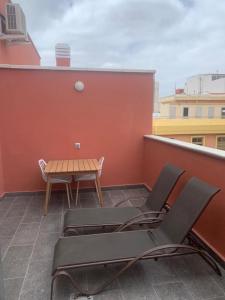 un patio con 2 sillas y una mesa en el techo en Rosamar Las Canteras Áticos con terraza, en Las Palmas de Gran Canaria