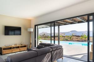 a living room with a couch and a tv and a pool at Villa Alfa by FuerteventuraVillas in Lajares