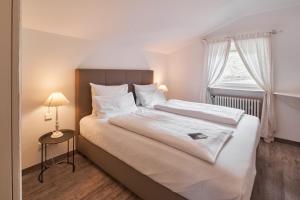 Schlafzimmer mit einem großen weißen Bett und einem Fenster in der Unterkunft Seehaus Riessersee in Garmisch-Partenkirchen