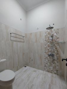 a bathroom with a toilet and a stone wall at Saira Hotel dan Homestay Syariah in Sleman