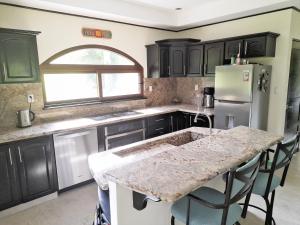 a kitchen with black cabinets and a marble counter top at Beautiful Lake Arenal 2 Bed Villa - Plus Communal Pool, Gym, Massage in Tronadora