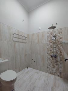 a bathroom with a toilet and a stone wall at Saira Hotel dan Homestay Syariah in Sleman