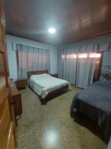 a bedroom with two beds and a window with curtains at HOSTEL DEL HERRERO in Apóstoles