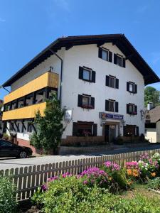 un bâtiment blanc avec des fenêtres noires et une clôture dans l'établissement Hotel Tannenhof, à Bodenmais