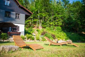 two wooden benches sitting in the grass near a house at Chata Pod Desenským vrchem in Desná