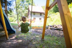 a little girl sitting on a swing in a playground at Chata Pod Desenským vrchem in Desná