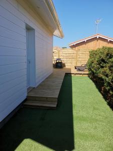 a house with a wooden porch and a lawn at La Caza Cozy in La Teste-de-Buch