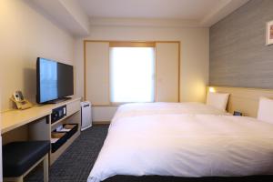 Habitación de hotel con cama grande y TV en Dormy Inn Premium Ginza, en Tokio