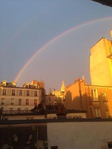 a rainbow over a city with buildings at Montmartre Bright & Quiet in Paris
