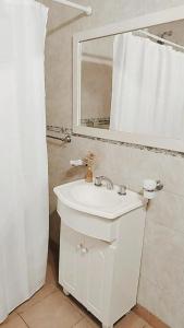 Baño blanco con lavabo y espejo en Departamentos Ventana en Sierra de la Ventana