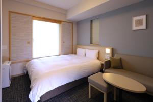 um quarto de hotel com uma cama, uma mesa e uma cadeira em Dormy Inn Premium Ginza em Tóquio