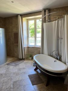 een grote badkamer met een bad en een raam bij Chez Jallot in Vidaillat