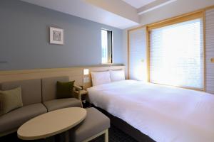 東京にある天然温泉　七宝の湯　ドーミーインPremium銀座のベッド、テーブル、ソファが備わるホテルルームです。