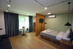 Schlafzimmer mit einem Bett, einem Tisch und einem TV in der Unterkunft Pine Aparthotel in Shekhvetili