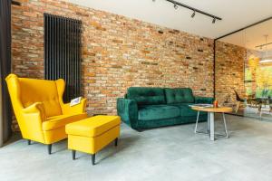 sala de estar con sofá verde y sillas amarillas en Stunning loft-style apartment en Varsovia