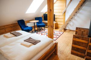 a bedroom with two beds and two blue chairs at Nestville Apartments in Hniezdne
