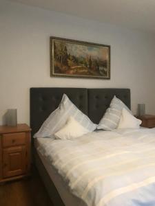 - un lit avec des oreillers blancs et une photo sur le mur dans l'établissement Hotel Tannenhof, à Bodenmais