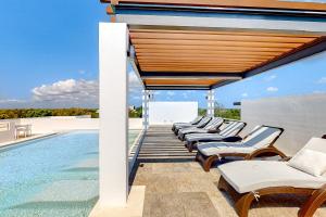 a row of lounge chairs next to a swimming pool at La Selva 303 Sirenis in Akumal