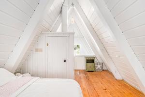 1 dormitorio blanco en el ático con techo blanco en Mt McSauba A Frame Cottage, en Charlevoix