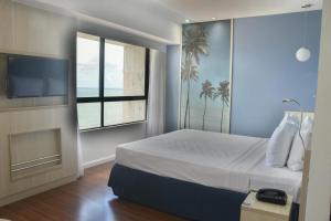 a bedroom with a bed and a tv and a window at Mercure Recife Navegantes in Recife